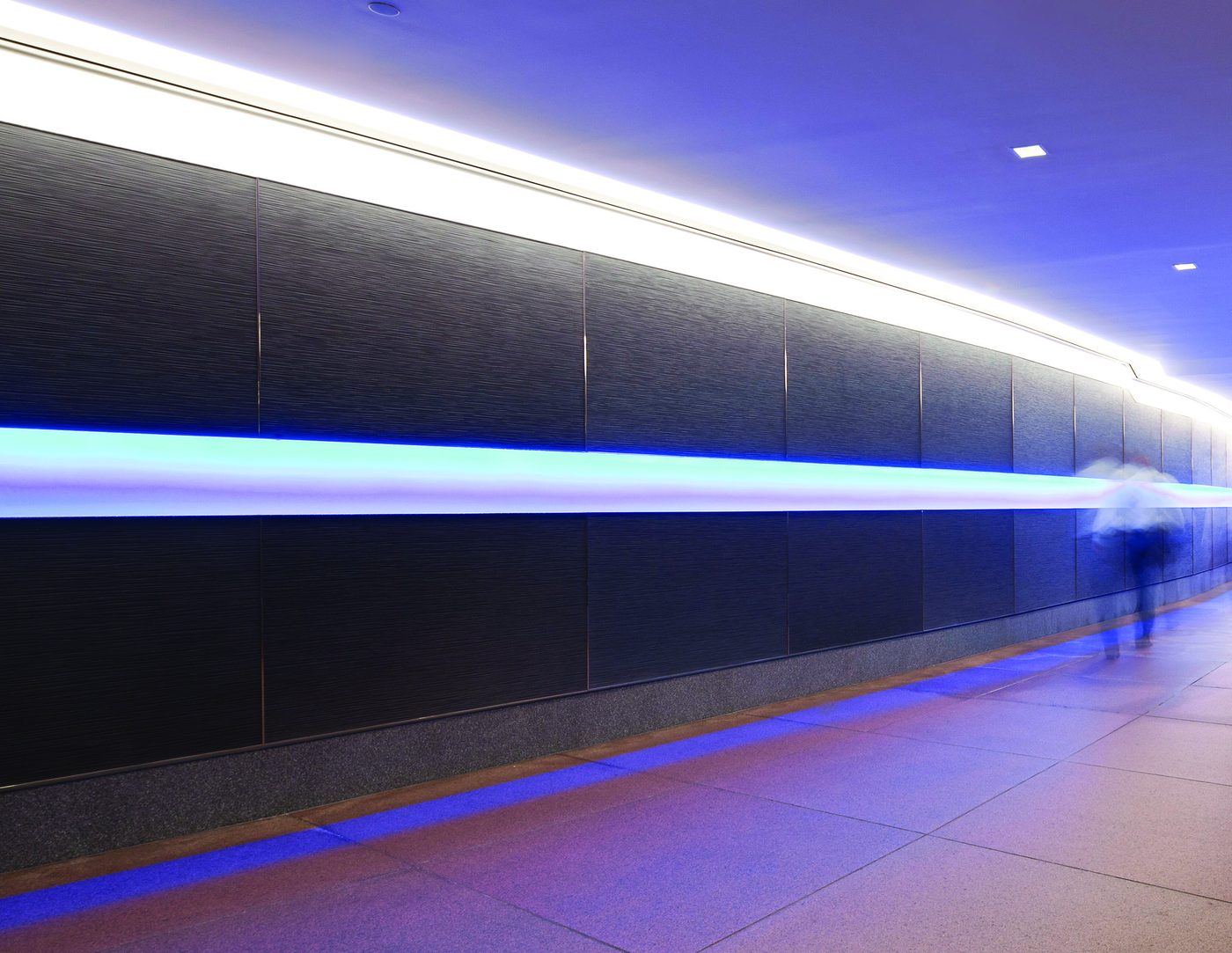 Backlit corridor wall clad in cast bonded metal